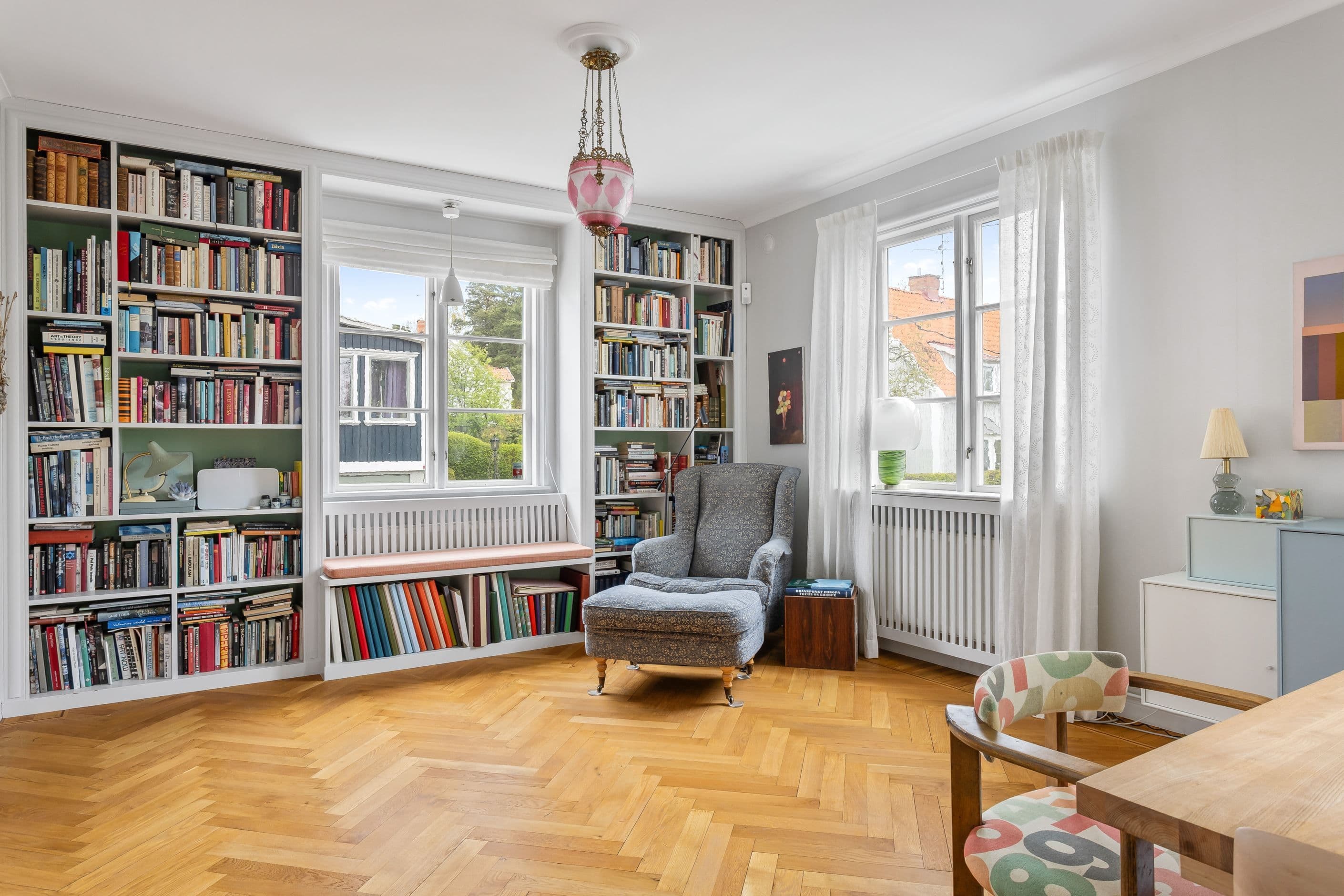 Trivsam läshörna i bibliotek med platsbyggda hyllor och sittbänk