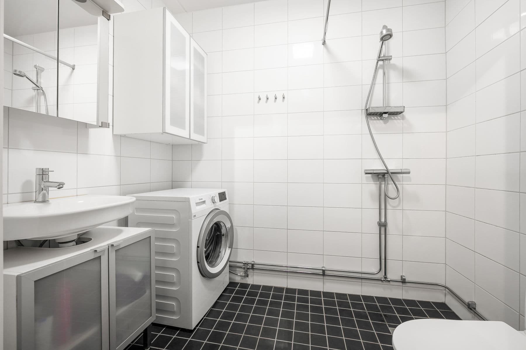 Modernt badrum med tvättmaskin och flera skåp