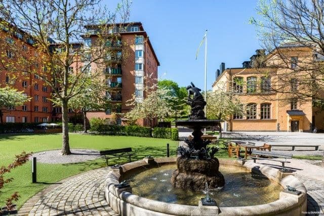 Underbart ljus fin gård med porlande fontän, flaggstång, lekytor och sittplatser