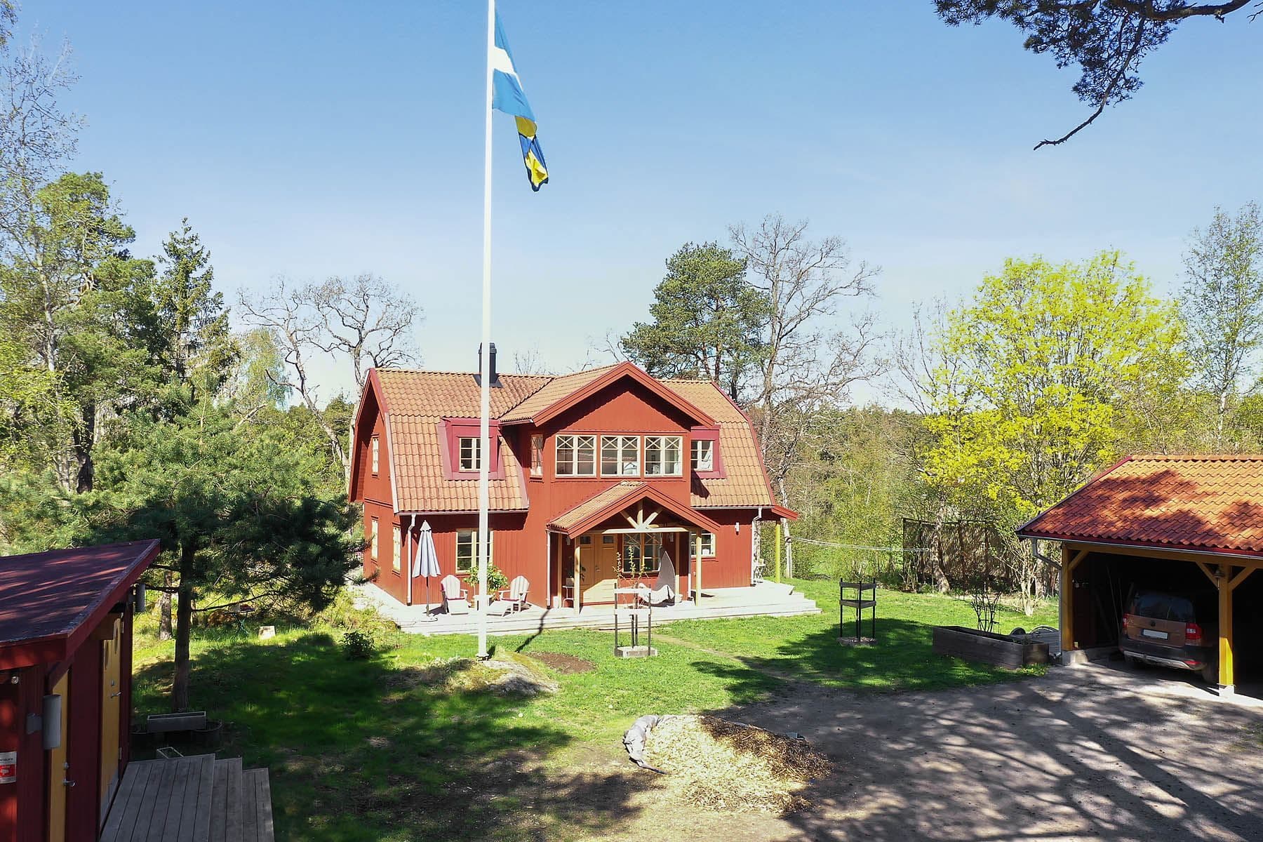 Stor fin framsida med carport och förråd