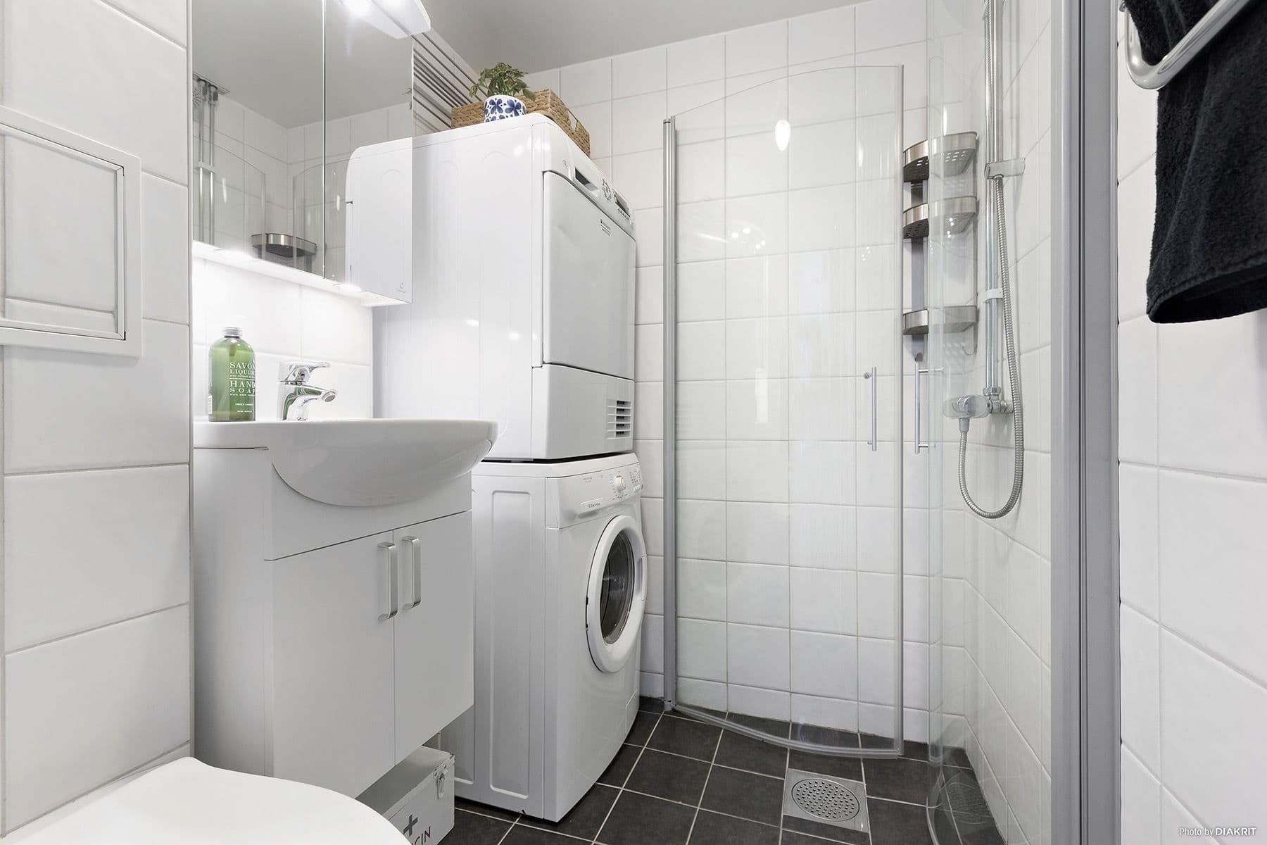 Snyggt helkaklat badrum med tvättmaskin och torktumlare