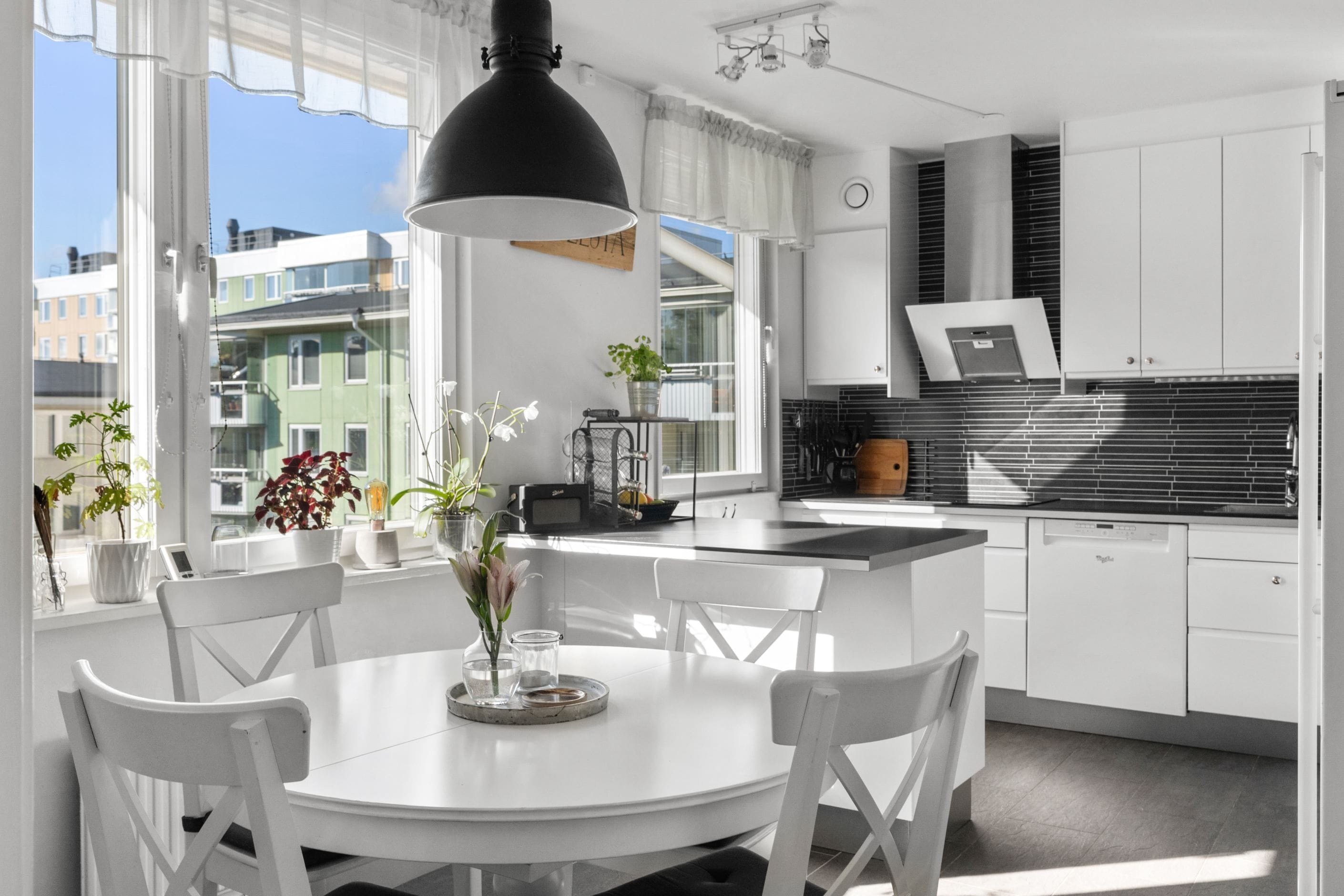 Stilrent kök med praktisk köksö och plats för matbord samt stolar