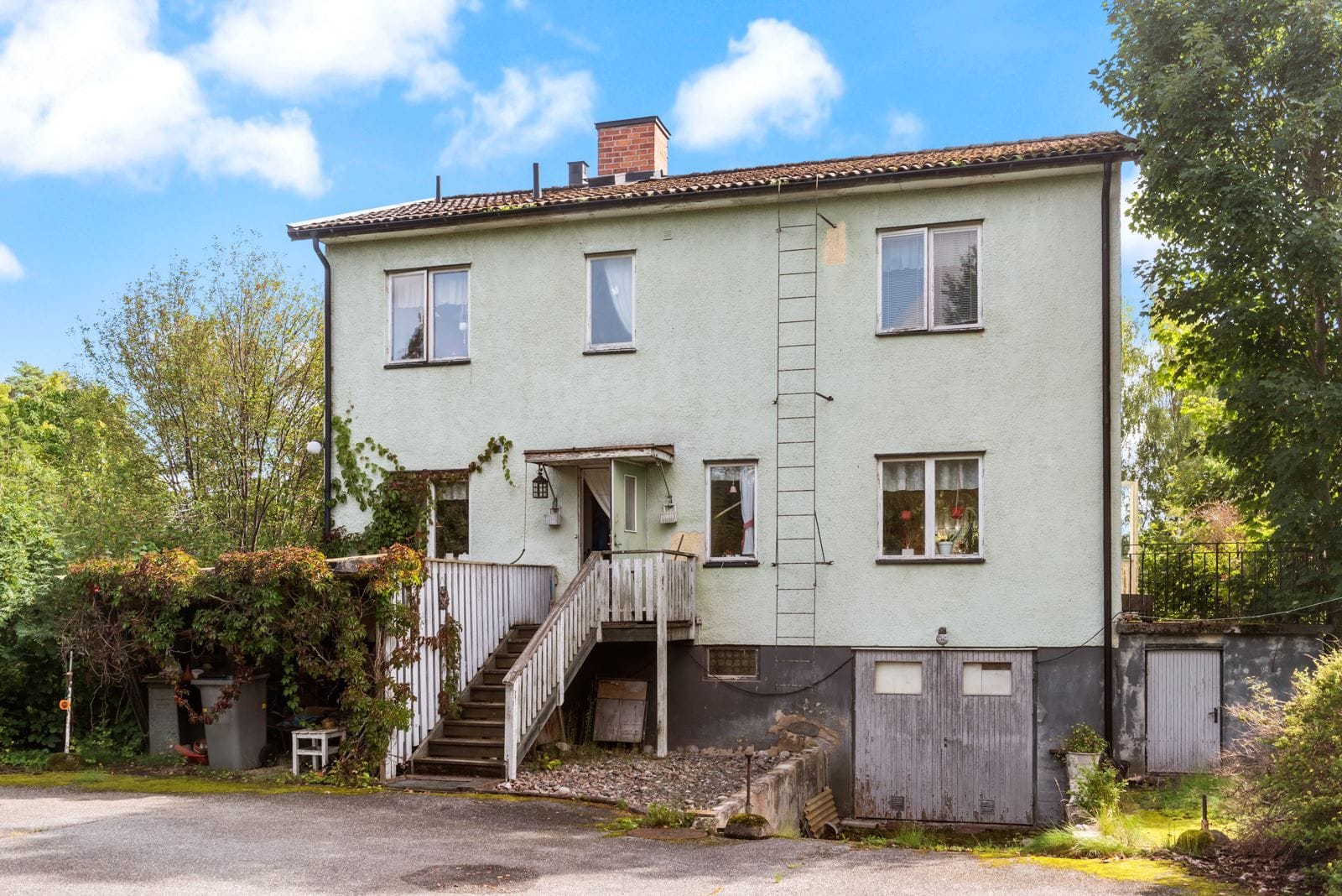 Bild på huset från trädgårdssidan. Asfalterad infart.