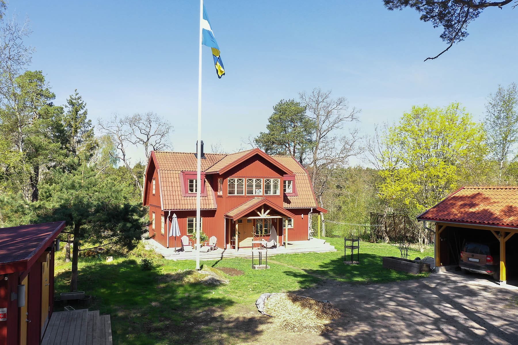 Stor fin framsida med carport och förråd